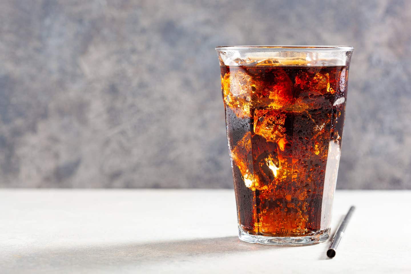 glass of cold cola soft drink with ice on wooden background