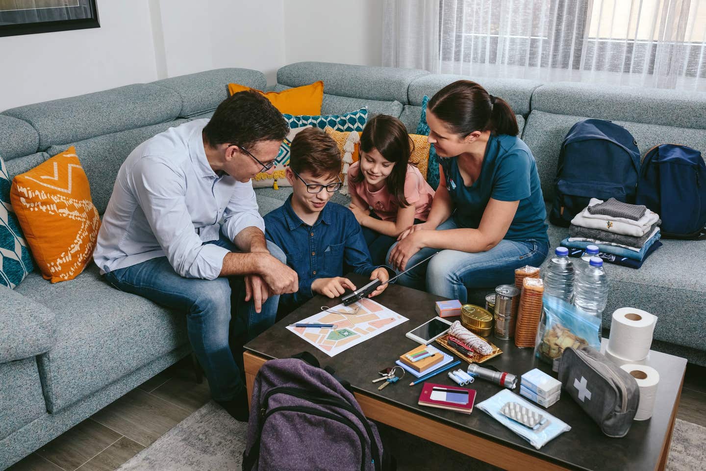 Parents explaining to their children how to use the radio while preparing emergency backpacks