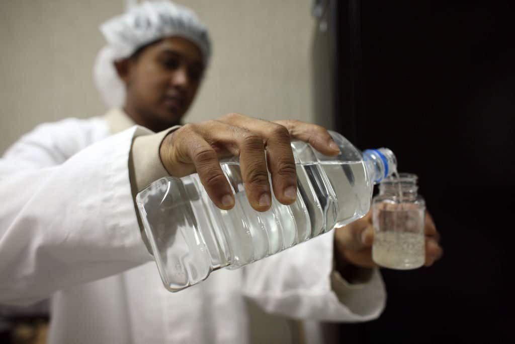 HELMAND PROVINCE, AFGHANISTAN - JULY 21: A KBR (UK) employee test for the bacteriological content in a sample of water at the water testing laboratory, at the Camp Bastion Water Bottling Plant on July 21, 2008 at the British Army base in Camp Bastion in the Helmand Province, Afghanistan. The Bastion Water Bottling Plant supplies and delivers bottled drinking water and bulk drinking water for all of the coalition forces and contractors that live and work in Camp Bastion. The water's also supplied to the Forward Operating Bases (FOBs) by road or air drop via the military chain.The bottling plant has its own Water Testing Laboratory where it is tested according to European Directive. Mainly workers are from Sri Lanka and Nepal and are employed in the plant that has been open now for about 22 weeks and has produced 2,634,284 litres of bottled drinking water, of which 2,512,180 litres have already been delivered to the troops on the ground. (Photo by Marco Di Lauro/Getty Images)