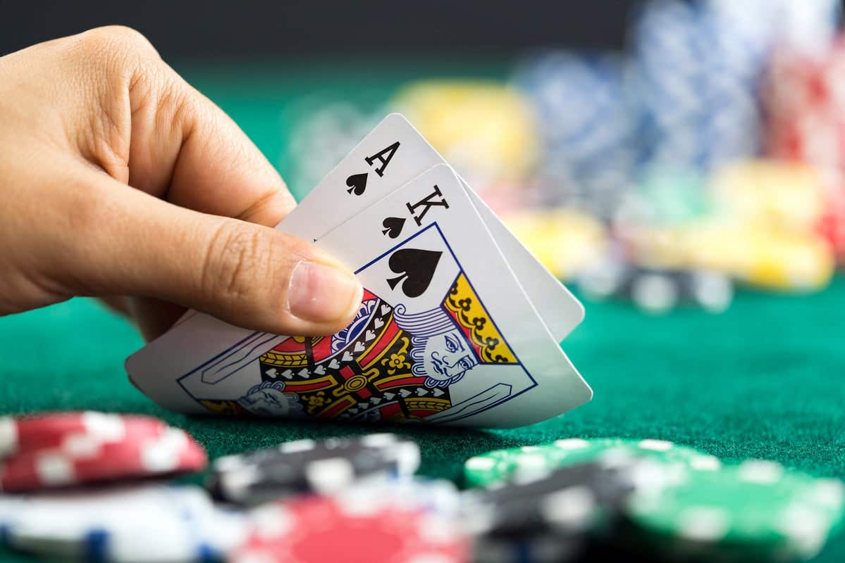 Gambling Hand Holding Poker Cards and Money Coins Chips